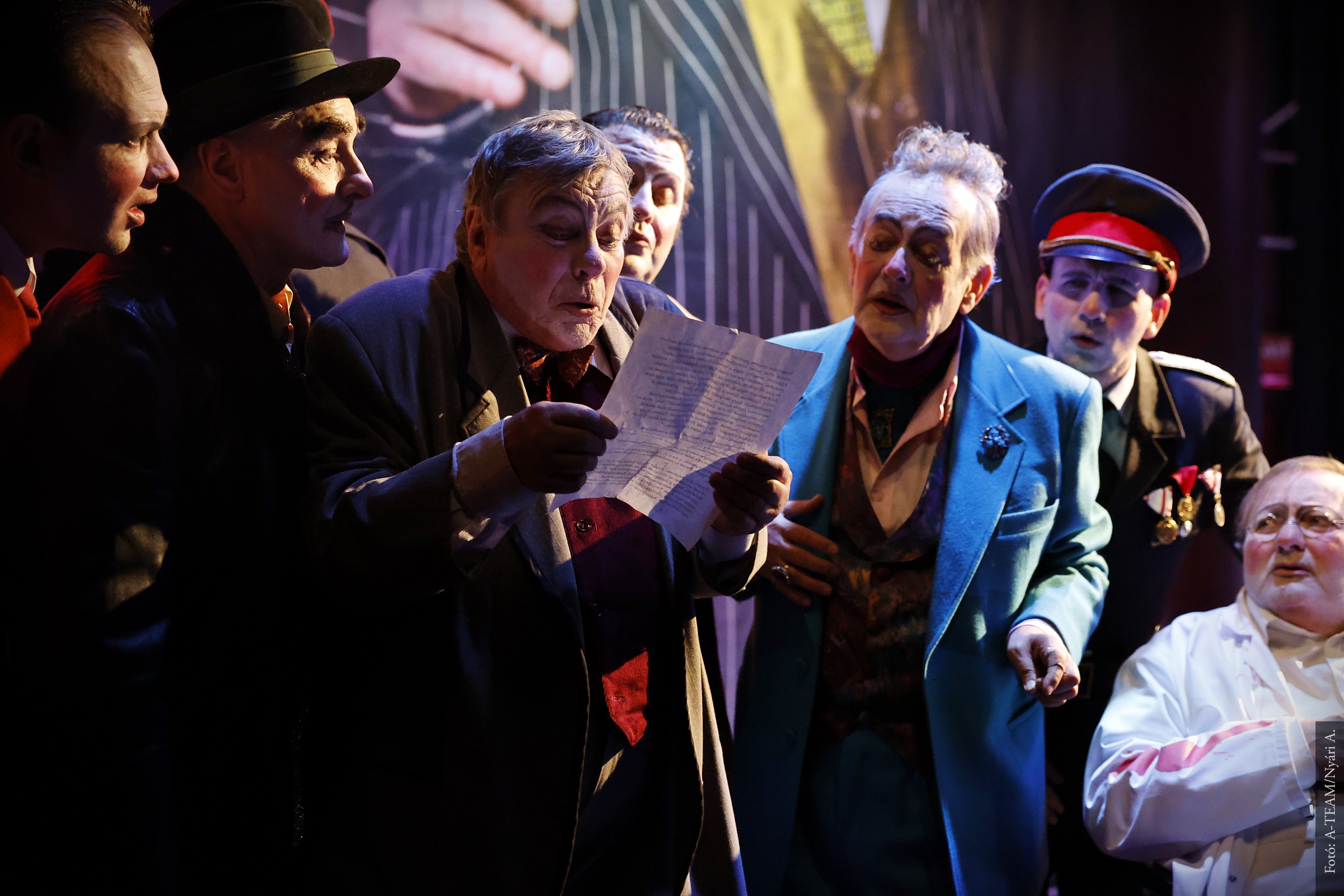 A színművész A revizor című darabban jelenet közben levelet olvas, a többiek körülállják.