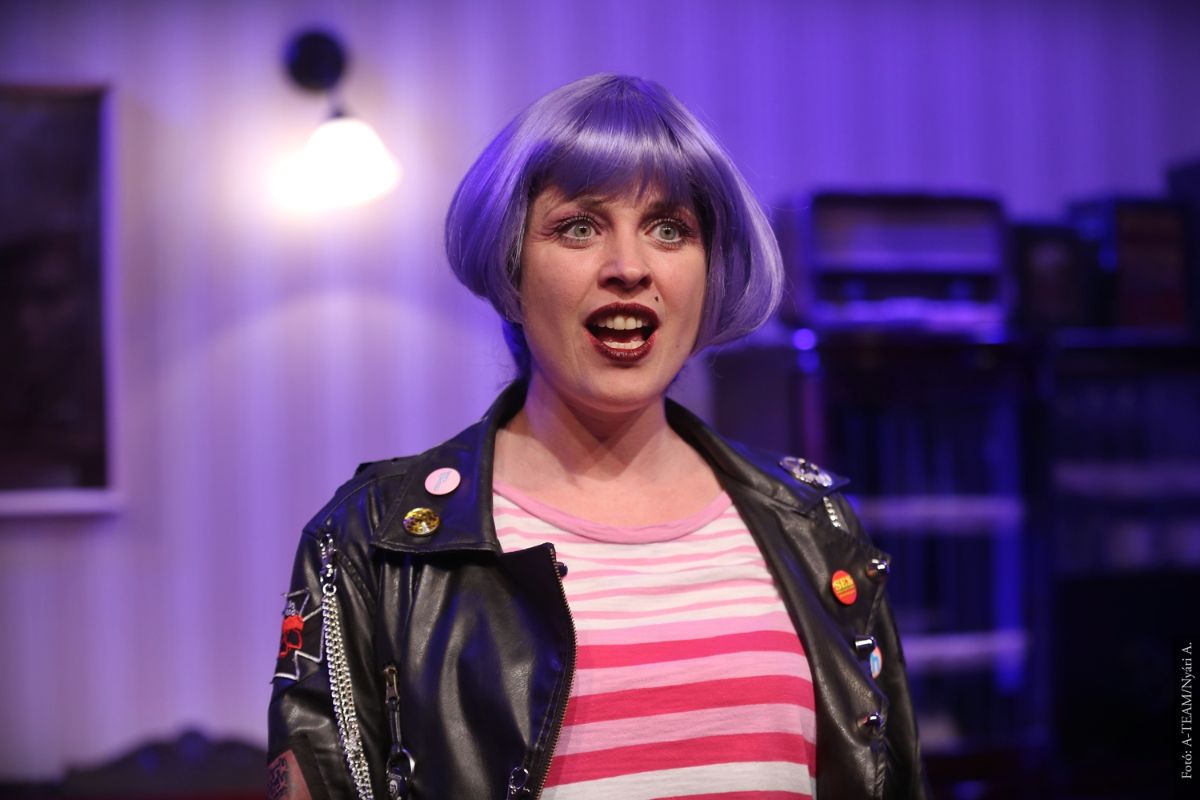 A színművész Az utolsó hősszerelmes című darabban jelenet közben, lila parókában beszél.