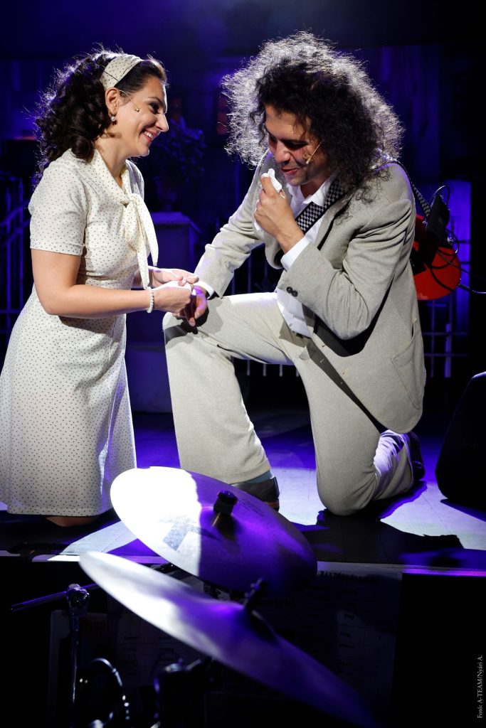 Azok a boldog szép napok című színházi előadás romantikus jelenete, ahol a férfi féltérdre ereszkedve beszél a mosolygó nőhöz.