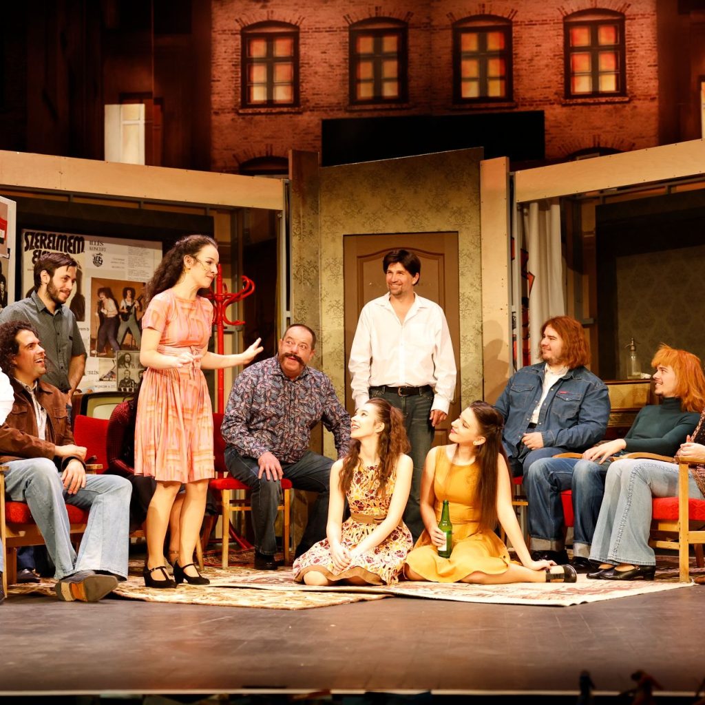 Azok a boldog szép napok című színházi előadás egyik jelenete, ahol a szereplők beszélgetnek és nevetnek a színpadon.