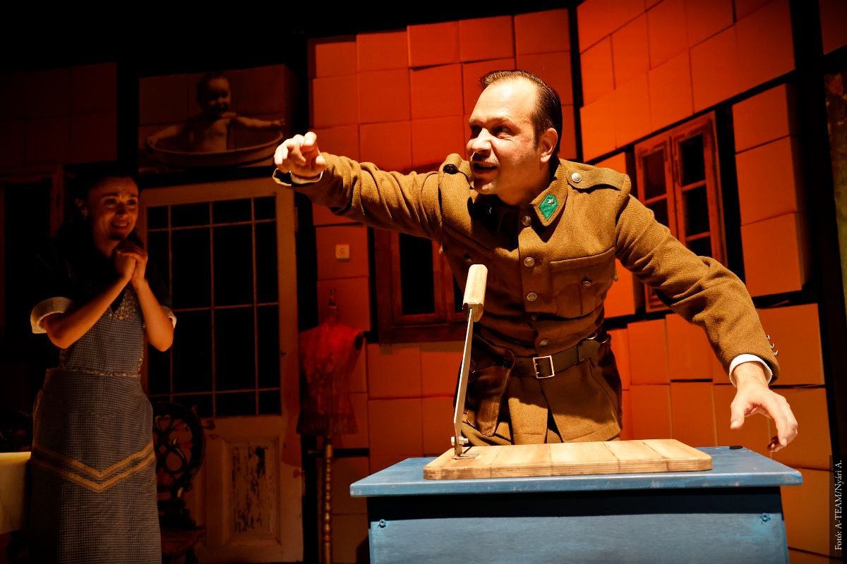 A színművész a Tóték című darabban jelenet közben margóvágóval, háttérben egy másik színművész izgatottan nézi.