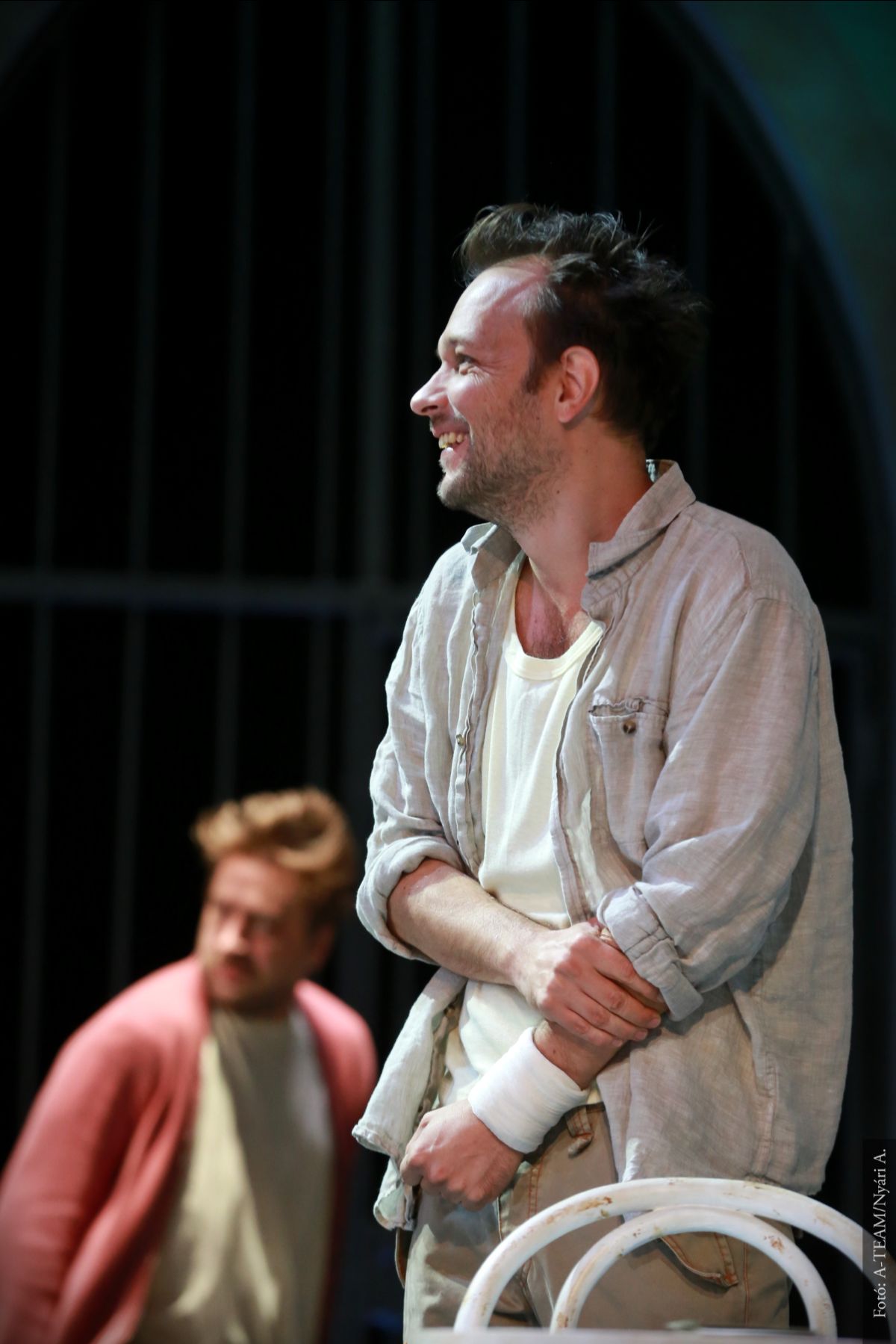 A színművész a Kakukkfészek című darabban jelenet közben, háttérben egy másik színművésszel.