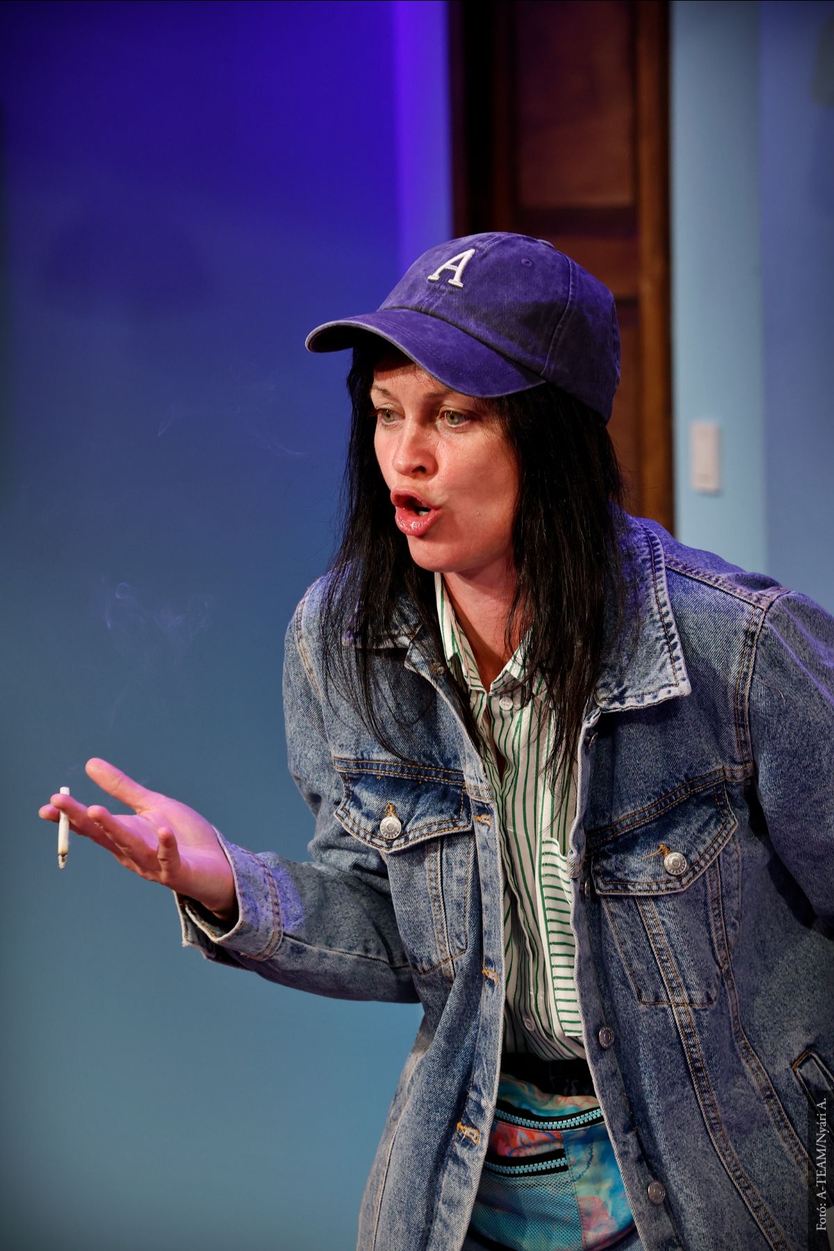 A színművész a Furcsa pár című darabban jelenet közben, jobb kezében cigarettával beszél.