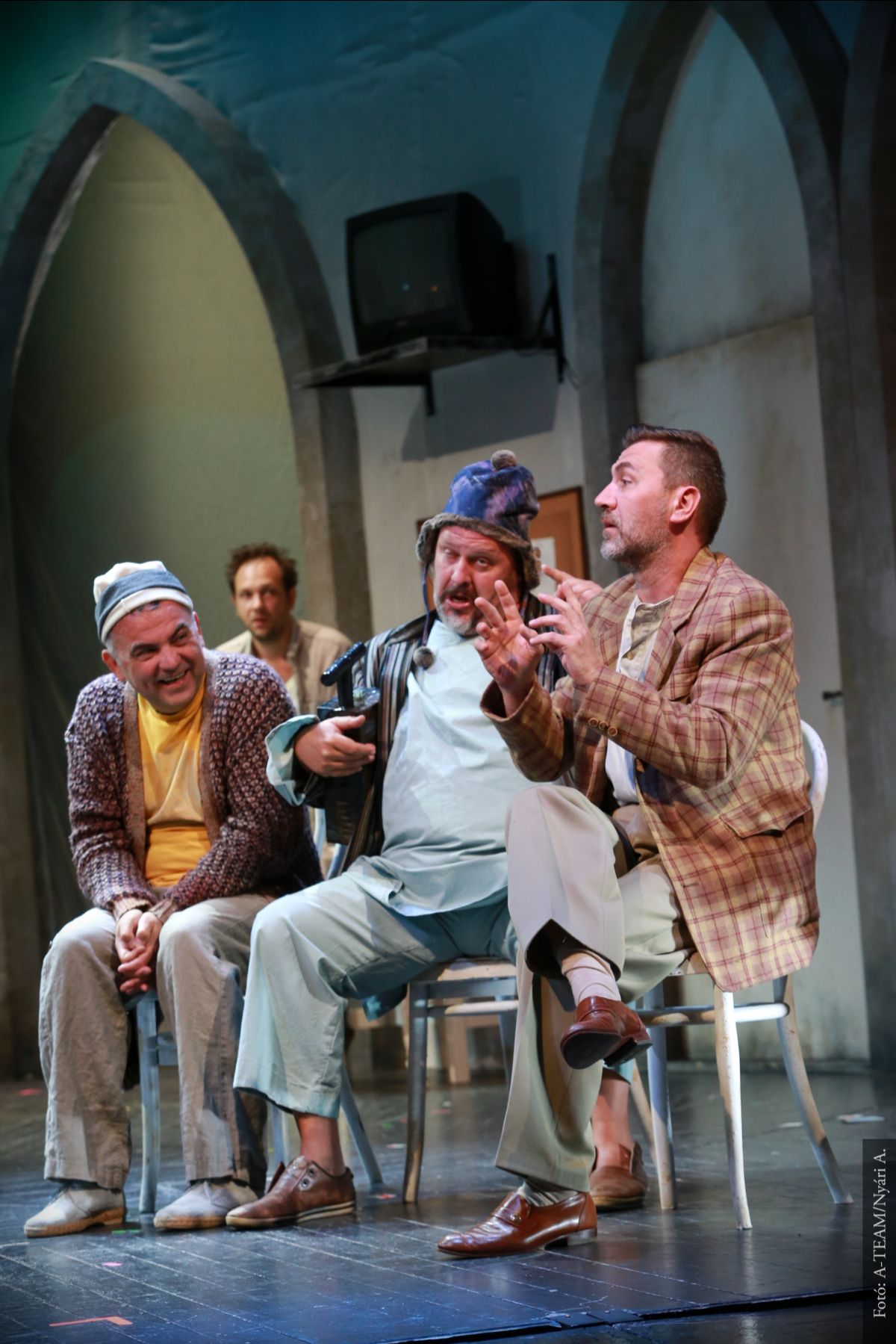 A színművészek a Kakukkfészek című előadásban jelenet közben a színpadon beszélgetnek.