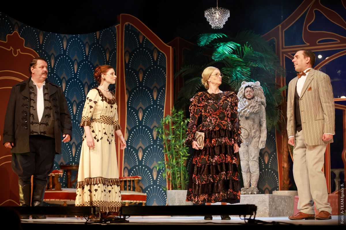 A színművészek a Kastély kölcsönbe című előadás egyik jelenetében a színpadon párbeszédet folytatnak.