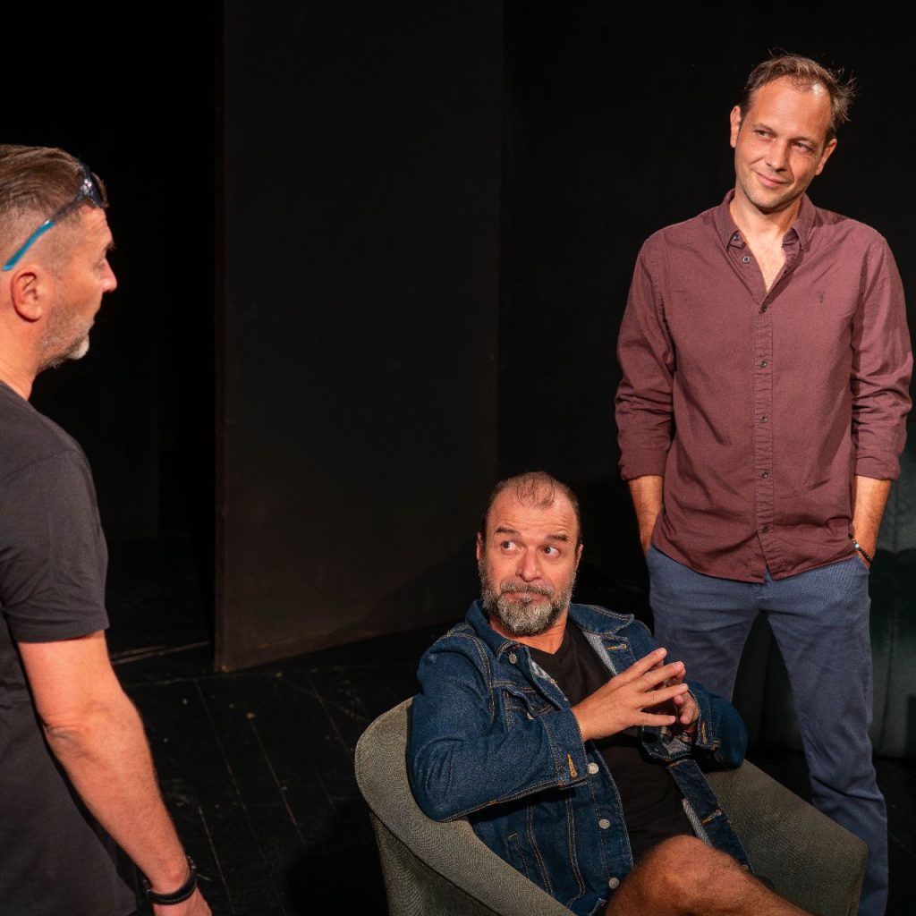 A Kék róka című előadás olvasópróbáján három férfi beszélget a próbateremben, egyikük ül, a másik kettő áll mellette.