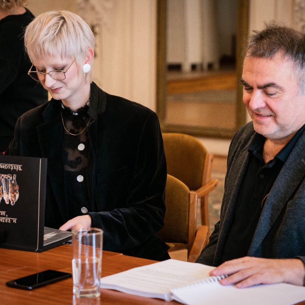 A Látni a láthatatlant című előadás olvasópróbáján két alkotó ül az asztalnál, előttük jegyzetek és laptop.