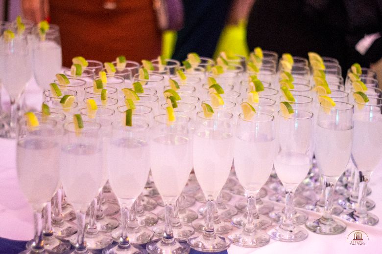 Rendeteg pezsgőspohár van a képen, amiben fehér ital van, a poharak pedig egy-egy lime szelettel vannak díszítve