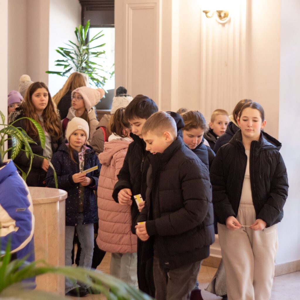 Sok kisgyermek sétál a színház fehér előterében.