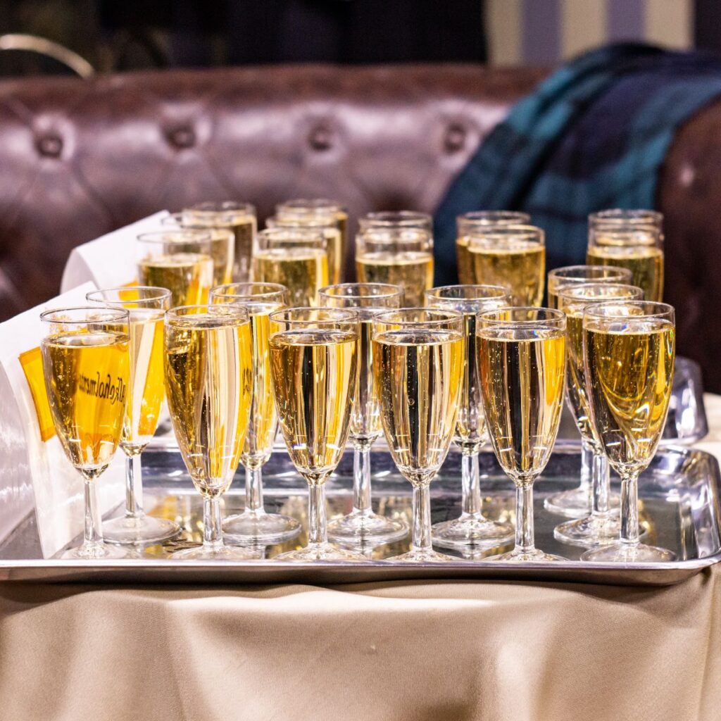 Az asztalon egy tálcán sorban pezsgővel töltött poharak vannak