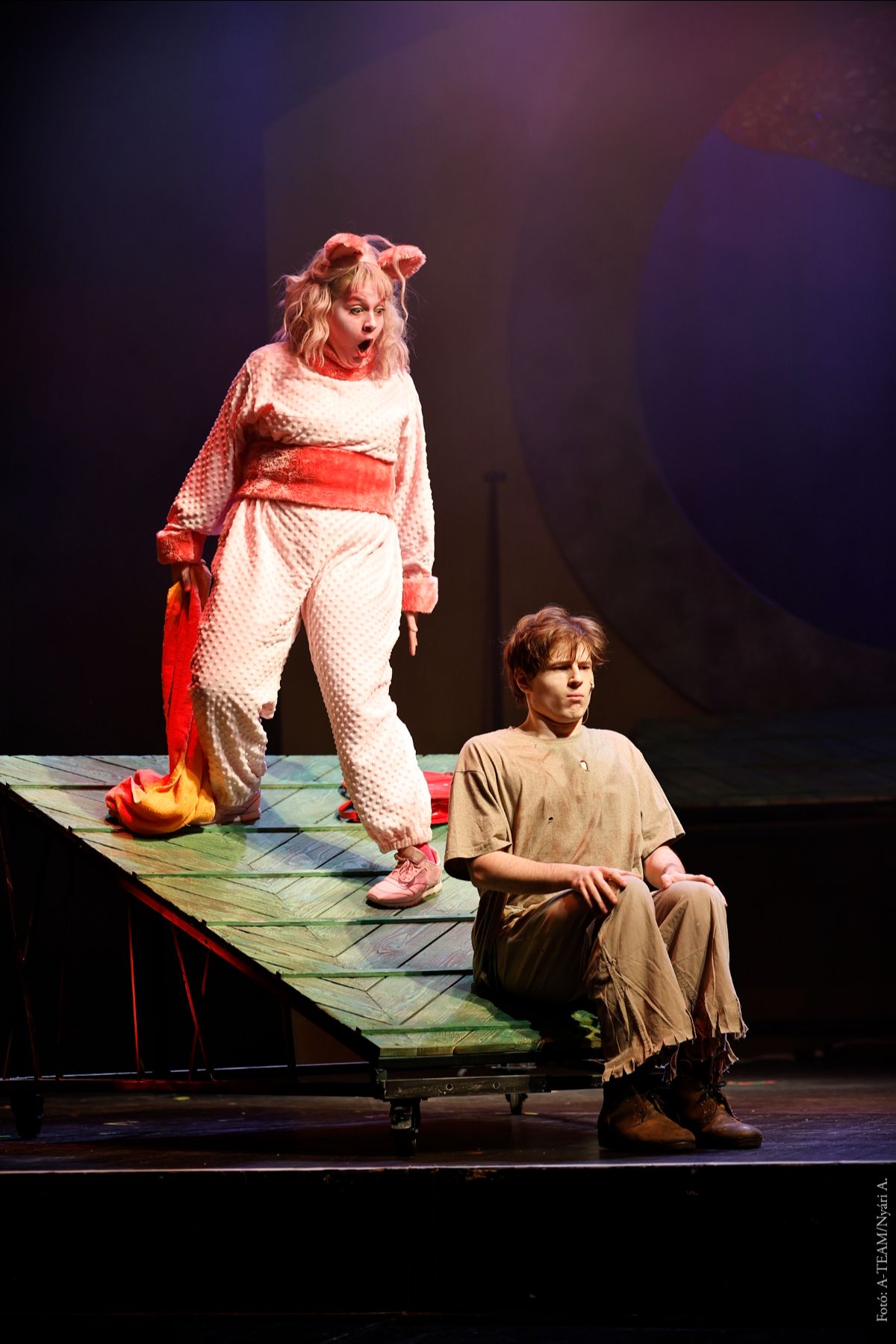 A színművész Az égig érő fa című darabban jelenet közben csodálkozik, előtte a másik színművész fegyelmezetten ül.