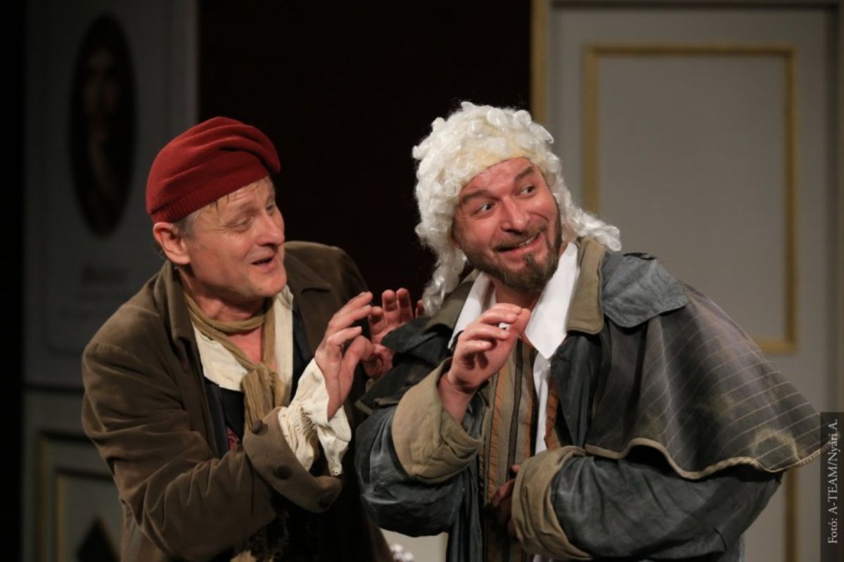 A színművészek a Fösvény című előadásban vidáman, jelenet közben a színpadon.