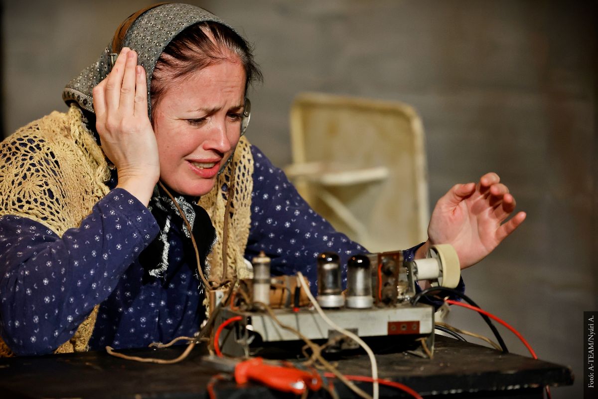 A színművész a Nyolcvan vödör levegő című darabban jelenet közben egyik kezét a fülére rakva kétségbeesve figyel.